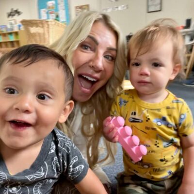 Founder and CEO Dr. Kimberly Regan smiles with 2 SNACS preschool students.